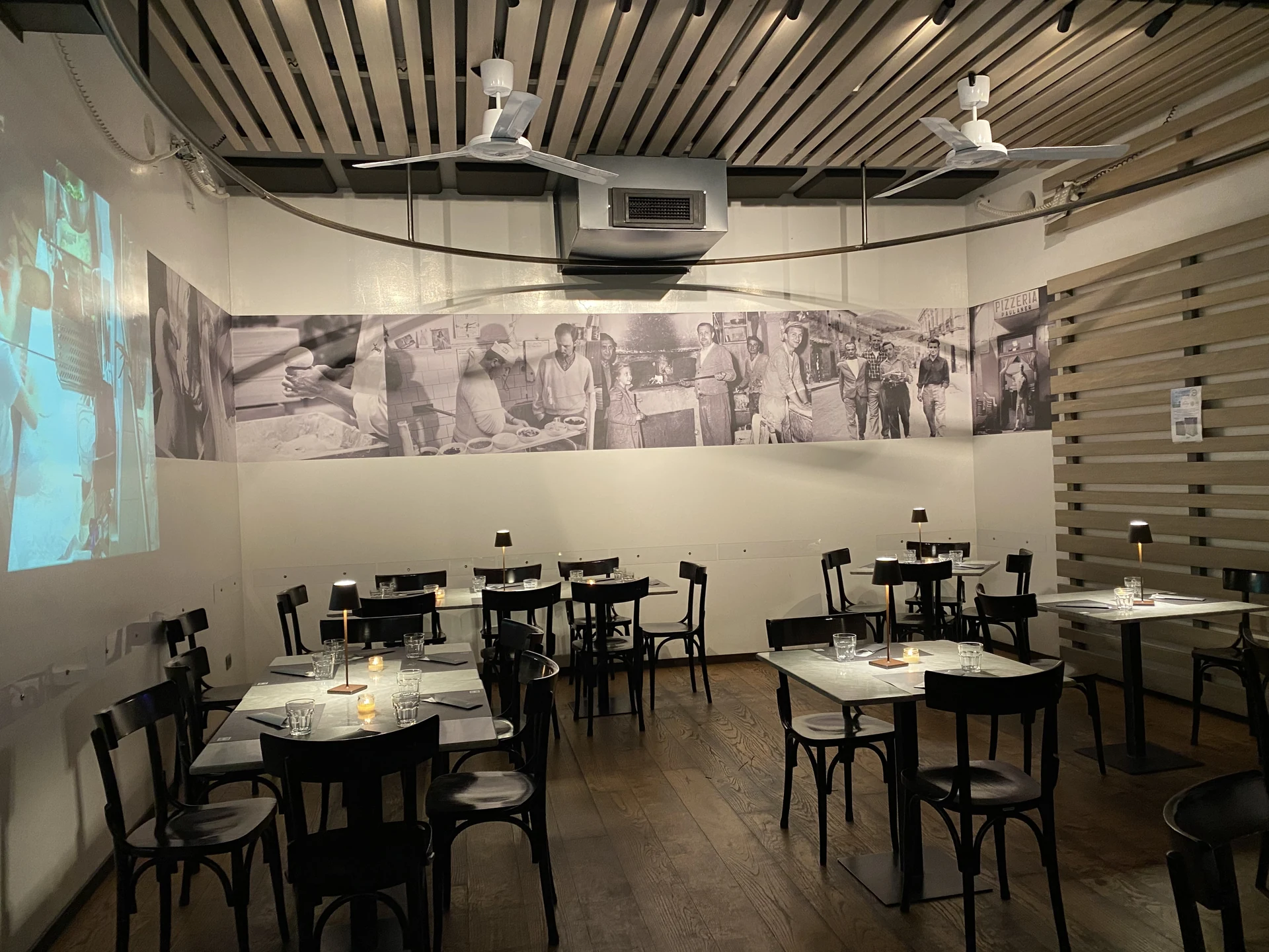 Sala ristorante Pepe in Grani con soffitto a doghe, parete fotografica storica illuminata e tavoli con lampade da tavolo